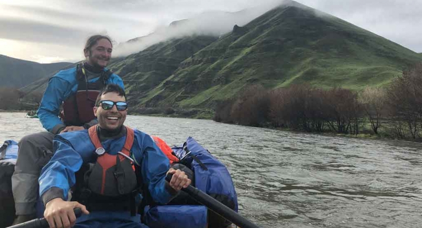 two gap year students smile while navigating a raft on an outward bound course 